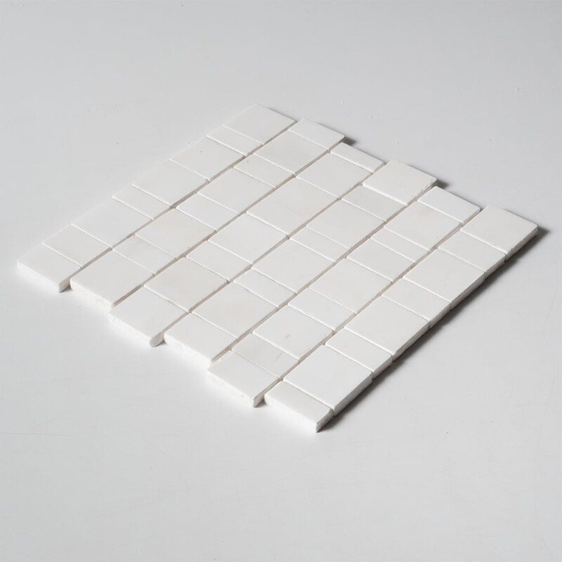 Side profile of a Bianco Dolomiti Honed Scarpa Rough Cut Marble Mosaic sheet, showing the 1/2 inch tile thickness and mesh backing that holds the individual hand-clipped marble pieces together.