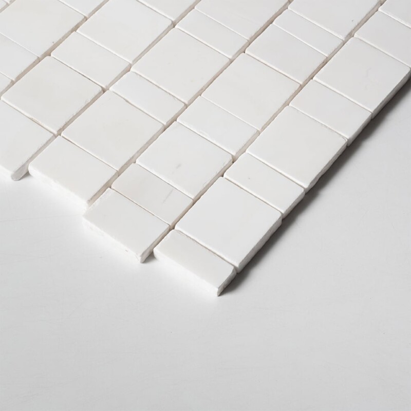 Angled perspective of Bianco Dolomiti Honed Scarpa Rough Cut Marble Mosaic tile, capturing the irregular hand-clipped edges and staggered joint pattern that give the surface its dimensional, rough-cut texture.