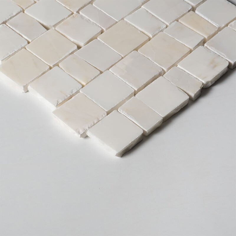 Angled perspective of Calacatta Amber Honed Scarpa Rough Cut Marble Mosaic tile, capturing the irregular hand-clipped edges and staggered joint pattern that give the surface its dimensional, rough-cut texture.