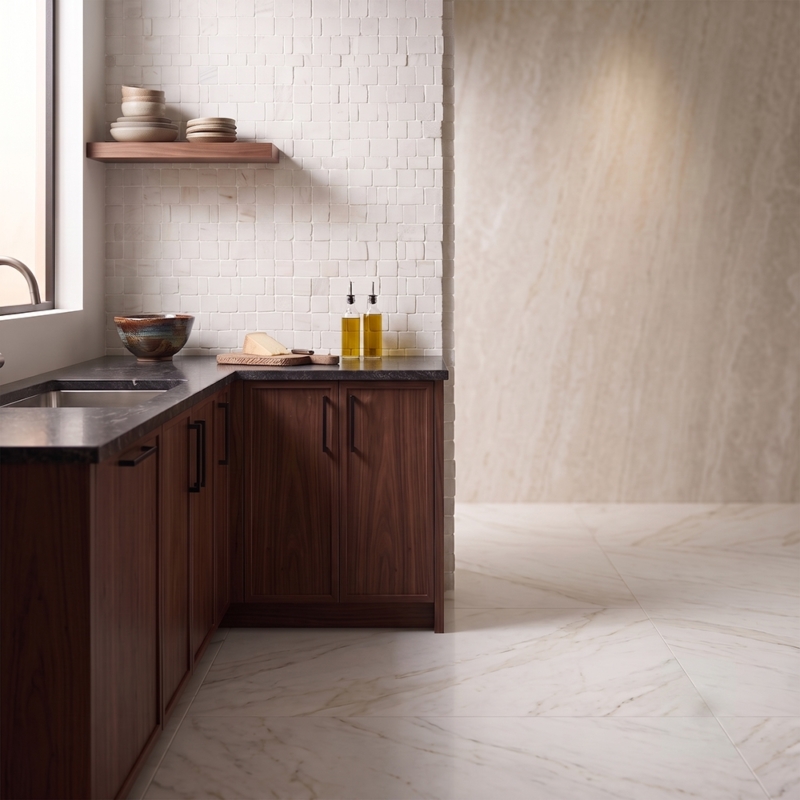 Calacatta Amber Honed Scarpa Rough Cut Marble Mosaic installed on a kitchen wall beside the window, showing the white marble's staggered pattern and amber-gold veining used as a backsplash-style accent in natural light.