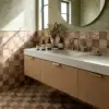 Travertine mosaic tile covering the bathroom floor and wainscoting in a cottagecore bathroom with floral wallpaper, light oak vanity, and brushed brass faucet.