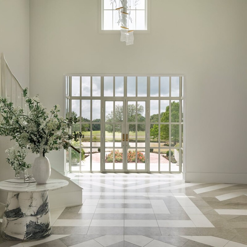 Bright hallway with limestone flooring and natural light creating airy elegant atmosphere by Country Floors