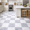 bright kitchen with soft gray checkerboard marble flooring and wooden stools by Country Floors