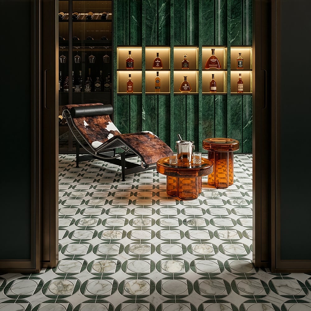 Calacatta green marble mosaic floor tile in retro circular geometric pattern inside a luxury home bar and wine cellar, deep green fluted marble walls with backlit bottle shelving, Le Corbusier chaise longue and amber glass side tables
