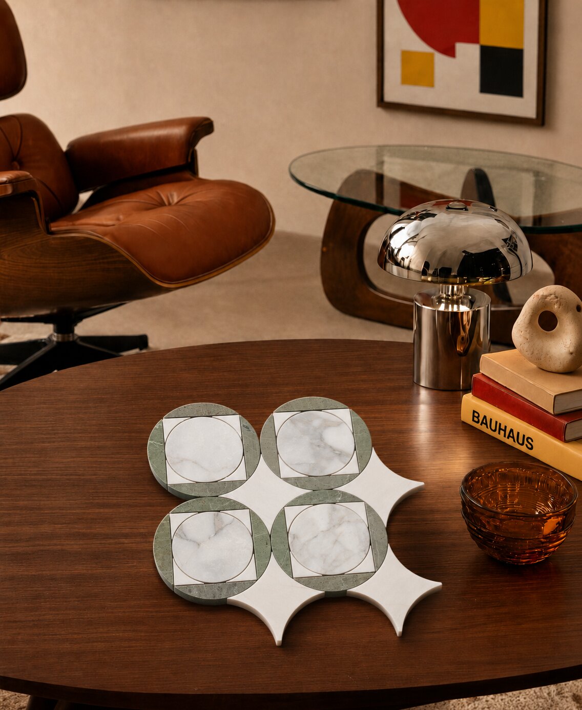 Neo deco tile design featuring a bold circle and square marble mosaic in forest green marble and Snow White, displayed on a walnut coffee table alongside an Eames lounge chair, chrome mushroom lamp, Bauhaus design books and amber glass bowl in a Mid-Century Modern living room