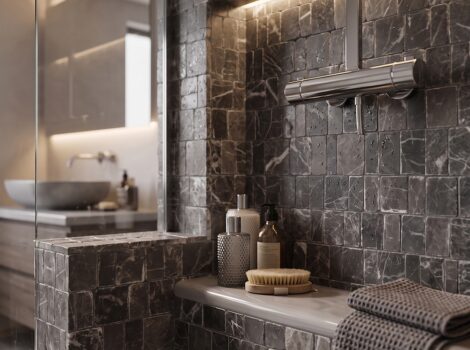 Revestimento de azulejos Scarpa em mosaico preto polido, na cor Iris, cobrindo toda a parede do chuveiro e o banco embutido em mármore carvão escuro com veios brancos, exibindo a textura da superfície molhada e o padrão irregular de corte manual. Inclui também um chuveiro de teto cromado e uma toalha em tecido waffle.